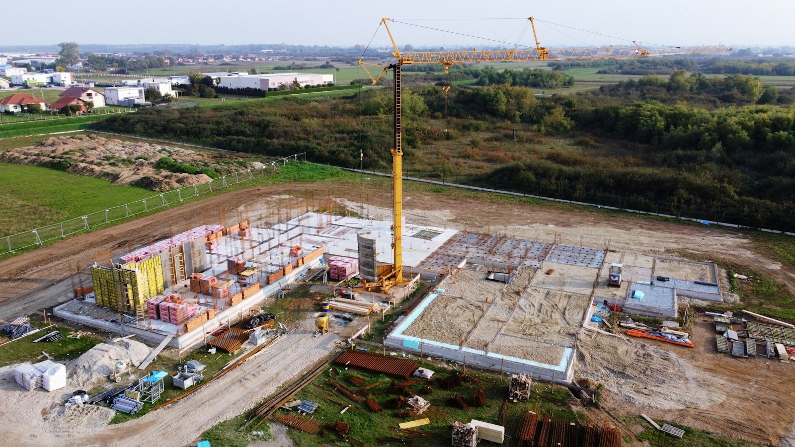 Aerial view of a construction site with a tower crane and building foundations